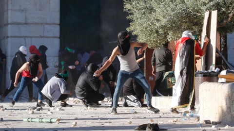 Los palestinos se enfrentan con la policía israelí dentro del complejo de la mezquita de Al-Aqsa después de que la policía israelí ingresara al complejo antes del amanecer mientras miles de musulmanes se reunían para rezar durante el mes sagrado del