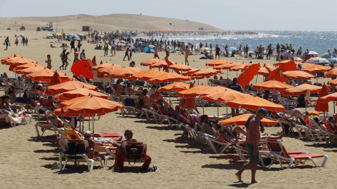 turistas disfrutan este jueves en la playa de Maspalomas (Gran Canaria), donde se registran cielos despejados y temperaturas sobre los 24 grados.