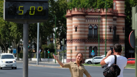 Una turista se fotografía bajo un termómetro que marca 50ºC hoy en Sevilla. EFE/Pepo Herrera