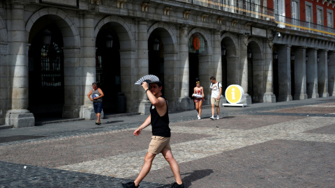 Un hombre sujeta un abanico sobre su cabeza para intentar protegerse de los fuertes rayos del sol en Madrid. REUTERS/Javier Barbancho