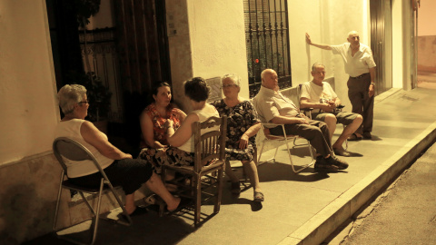 Un grupo de ancianos sale a las puertas de sus casas para intentar evitar el calor de la noche. REUTERS/Jon Nazca