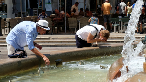 Un grupo de turistas moja sus cabezas con agua de una fuente pública en Valencia. REUTERS/Heino Kalis