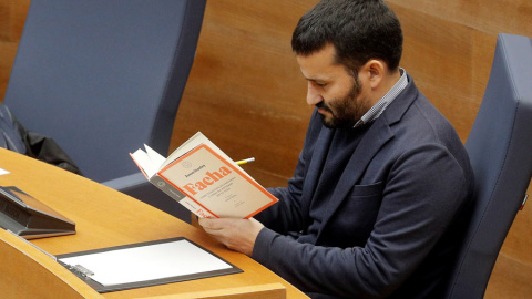 El conseller de Educación y Deportes de la Generalitat, Vicent Marzá, lee el libro 'Facha' durante la intervención del diputado de Vox, Jose María Llanos, en el debate en Les Corts Valencianes. (KAI FÖRSTERLING | EFE)