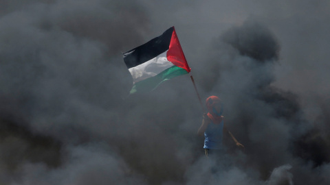 Un chico sostiene una bandera palestina en medio del humo durante las protestas contra el traslado de la embajada de EEUU a Jerusalén. / Reuters