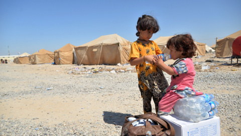 Niños iraquíes migrantes desde Siria reciben suministros de ayuda en un campamento de refugiados en Baiji, al norte de Bagdad. REUTERS/Stringer