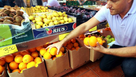 Un hombre al lado de unas naranjas en una frutería. EFE/Elvira Urquijo A.