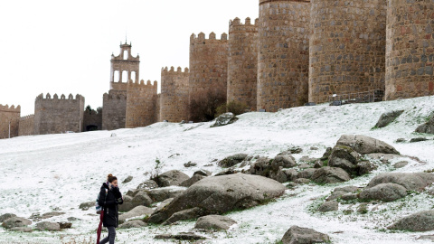 Una mujer camina junto al lienzo norte de la muralla de Ávila cubierta por una fina capa nieve caída en las últimas horas. EFE