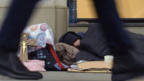 Un vagabundo duerme en la acera de la calle Passeig de Gracia en Barcelona el 29 de enero de 2019.