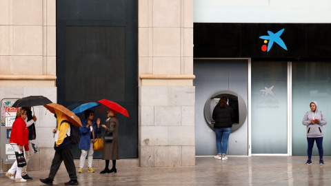 Una mujer utiliza el cajero automático de una oficina de CaixaBank en el centro de Málaga. REUTERS/Jon Nazca