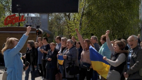 Vecinos de Jersón (Ucrania) gritan consignas y sostienen la bandera nacional de Ucrania durante una protesta en la que se les disparó gas lacrimógeno, en medio de la invasión rusa, el 27 de abril de 2022.