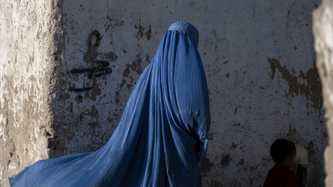 Una mujer afgana vestida con burka camina con un niño en Kabul el 28 de abril de 2022.