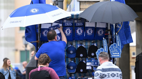 Un vendedor instala su puesto de mercadería fuera de Stamford Bridge antes del partido de fútbol de la Premier League inglesa entre Chelsea y Wolverhampton Wanderers, en Londres el 7 de mayo de 2022. Chelsea confirmó el sábado que un consorcio liderad