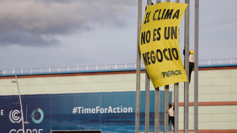 Varios activistas de Greenpeace despliegan una pancarta en una torre de iluminación del recinto ferial IFEMA, en la jornada final de la Cumbre del Clima COP25, este viernes, en Madrid. Los activistas protestan contra la "mercantilización de las negociac