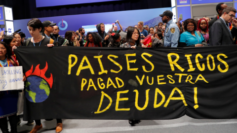 Manifestantes con un cartel en el que se lee: "Países ricos pagad vuestra deuda!"./ Susana Vera (Reuters)