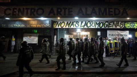 Un grupo de Fuerzas Especiales de Carabineros camina frente al cine Arte Alameda custodiado por voluntarios sanitarios el pasado viernes 13 de diciembre. /EFE