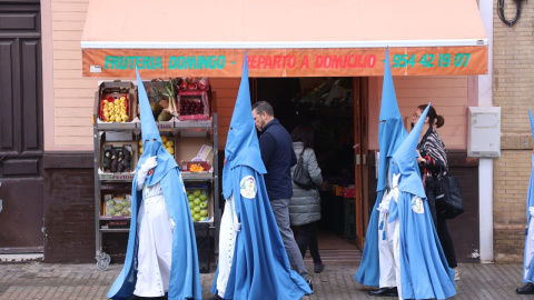 Varios nazarenos de la Hermandad de San Esteban llegando a su templo, en la Semana Santa de Sevilla 2022.