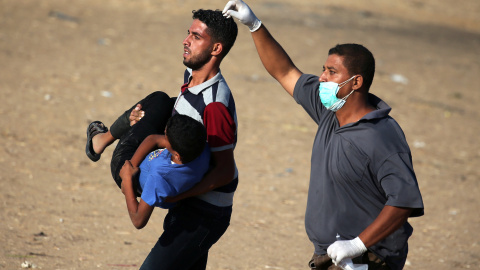 Dos hombres trasladan a un joven palestino herido durante las últimas protestas contra Israel. - REUTERS