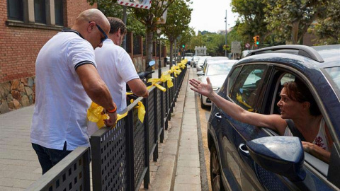 Una mujer increpa a miembros a dos personas que retiran lazos amarillos en la localidad de Alella. (ALEJANDRO GARCÍA | EFE)