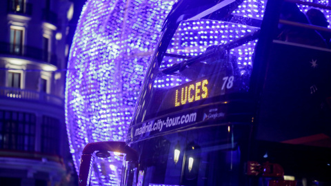 22/11/2019- Un autobús de turistas el que se lee en un panel luminoso "Luces", pasa junto a una bola gigante de Navidad encendida en Madrid. / EUROPA PRESS