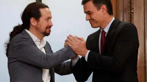 El candidato a la investidura, Pedro Sánchez (d), y el líder de Podemos, Pablo Iglesias (i), estrechan sus manos tras el acto de firma del acuerdo programático con las principales medidas que tomará el futuro Gobierno de coalición.EFE/JuanJo Martín