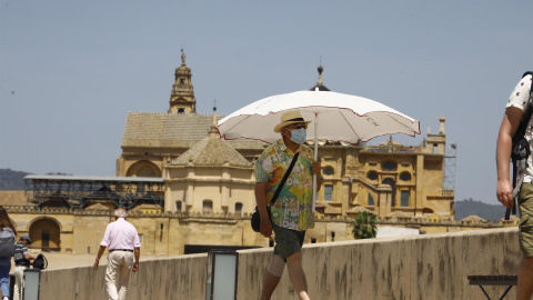 19/05/2022-Una persona se protege con una sombrilla del intenso calor mientras pasea este jueves 19 de marzo por el puente romano de Córdoba