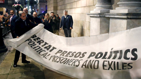 03/01/2020.- El presidente de la Generalitat Quim Torra (i) muestra la pancarta por la que la Junta Electoral Central le ha sancionado, ordenando que se le retire su credencial de diputado autonómico, lo que conlleva su inhabilitación. / EFE