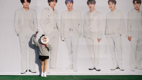 Una fan del grupo coreano de k-pop BTS posa junto a un cartel con los miembros de la banda. - AFP