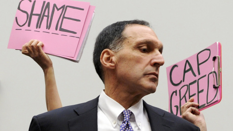 Algunos manifestantes sostienen pancartas detrás del presidente ejecutivo de Lehman Brothers, Richard Fuld, antes de iniciar su comparecencia en el Congreso de EEUU para explicar la quiebra de la entidad, y en la que aseguró que las autoridades estadoun