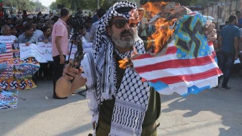 Un palestino quema una bandera de Estados Unidos en una protesta en el paso de Erez contra la decisión de la Administración Trump de suspender la financiación a la UNRWA. - AFP