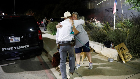 Una mujer que ofrece abrazos y oraciones abraza a un guardabosques de Texas fuera del Centro Cívico Ssgt Willie de Leon, donde los estudiantes habían sido transportados desde la Escuela Primaria Robb después de un tiroteo, en Uvalde, Texas , EE. UU. 24