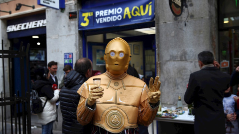 Una persona disfrazada del androide de la Guerra de las Galaxias C-3PO celebra en la administración de lotería 150 en la calle Arenal de Madrid. EFE/Rodrigo Jiménez