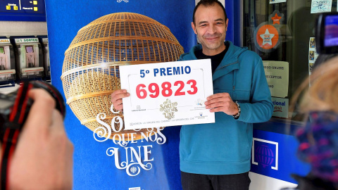 Enrique García, dueño de la administración 1 de La Virgen del Camino (León), posa con el número agraciado con el quinto premio del Sorteo. /EFE