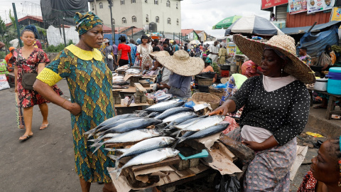 Una mujer habla con una vendedora de pescado en un mercado de Lagos, Nigeria