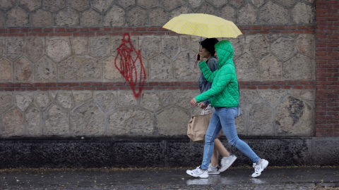 Varias personas caminan con paraguas el día en que han puesto en aviso amarillo a la Comunidad de Madrid por tormentas y lluvias, a 2 de mayo de 2022, en Madrid