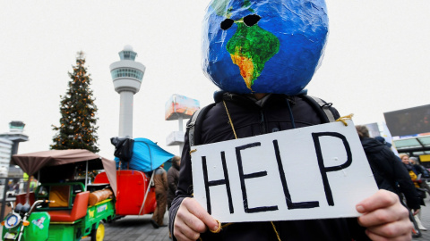 Un manifestante disfrazado de planeta Tierra sujeta un cartel en el que se puede leer "ayuda". REUTERS/Piroschka van de Wouw