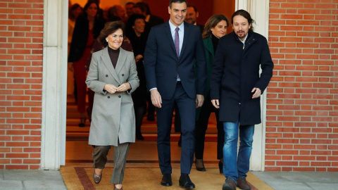 El primer ministro, Pedro Sánchez (C), camina junto a la vicepresidenta primera y ministra de Presidencia y Realciones con las Cortes, Carmen Calvo (i), y el vicepresidente de Derechos Sociales y Agenda 2030, Pablo Iglesias (d), momentos antes de posar p