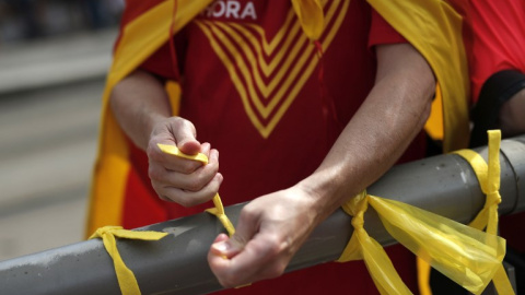 Un manifestante ata lazos amarillos. Los organizadores de la manifestación explicaron que tienen unos 460.000 inscritos. / AFP - PAU BARRENA