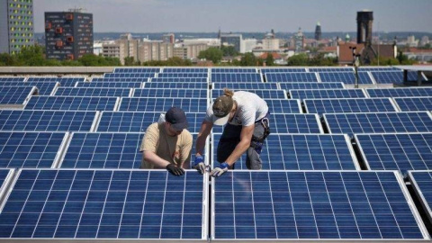 Dos operarios trabajan en las placas solares situadas en la azotea de un edificio. EFE