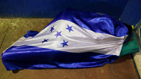 Uno de los migrantes durmiendo arropado por la bandera de Honduras. / Reuters