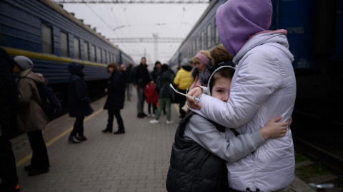 Una mujer abraza a un niño mientras un tren se prepara para salir de la estación principal de trenes en Zaporijia, en el sur de Ucrania, el 17 de abril de 2022.