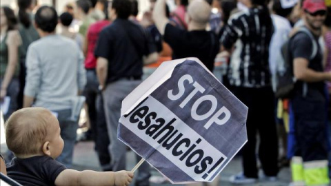 Un niño sujeta un cartel en una concentración contra un desahucio. EFE