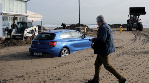 23/01/2020.- Un coche enterrado en la playa de de la Malvarrosa, en València, donde han comenzado las labores de limpieza tras el paso de la borrasca Gloria. / EFE - ANA ESCOBAR