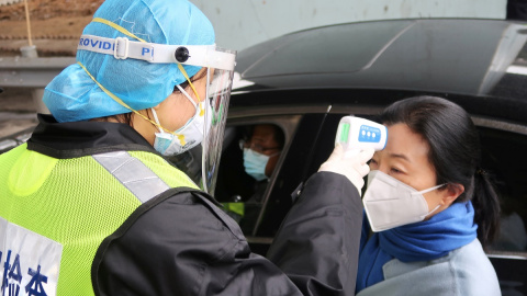 Un oficial de seguridad toma la temperatura a una pasajera tras el brote del coronavirus. REUTERS