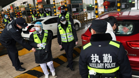 Oficiales de policía revisan el maletero de un coche en una ciudad fronteriza de Wuhan. REUTERS