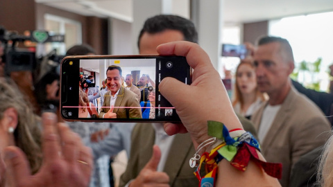 Una simpatizante saca una foto con su móvil al presidente de la Junta de Andalucía y candidato a la reelección, Juanma Moreno,  a su llegada a un acto público en Sevilla. E.P./Eduardo Briones