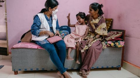 Vaishnavi, una paciente de tuberculosis resistente a los medicamentos de siete años, interactúa con una enfermera de MSF, mientras su madre la sostiene, en Mumbai.