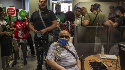 Activistas por el derecho a la vivienda protestan en una sucursal de CaixaBank en Vallecas (Madrid) para evitar una "oleada de desahucios".