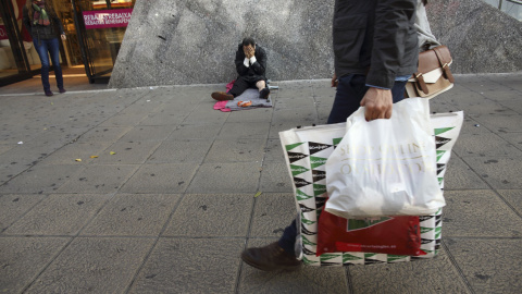 Un sin techo, en la puerta de un centro comercial en temporada de rebajas. REUTERS