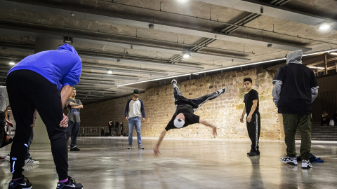 Un grup de joves practica break dance al costat de la muralla, del segle XVII.