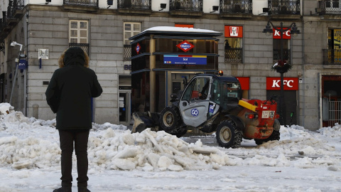 Una máquina quitanieves retira la nieve que aún permanece en la Puerta del Sol este martes en Madrid donde los colegios se encuentran cerrados, los supermercados desabastecidos y los hospitales intentando recuperar la normalidad tras días de aislamient